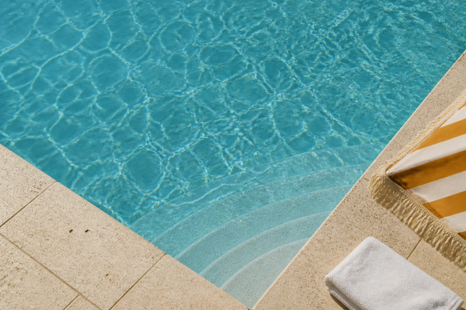 Sunlight rippling across turquoise pool water beside pale stone steps and a striped parasol; editorial illustration.
